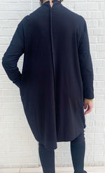 Load image into Gallery viewer, Back full body view of a woman wearing the moyuru black and white scribble dress. This dress is solid black on the back. This dress also has long sleeves and an asymmetrical neck.
