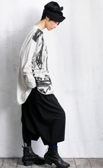 Load image into Gallery viewer, Right side full body view of a woman wearing black pants and the moyuru light grey scribble top. This top is light grey/white colored with an abstract black print all over the front. The top has long sleeves and a round neck.
