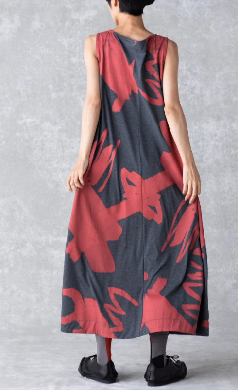Back full body view of a woman wearing the moyuru art print dress. This sleeveless dress is charcoal with a red abstract print and a-line silhouette.