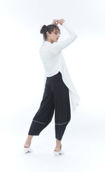 Load image into Gallery viewer, Back full body view of a woman wearing the mxmatthildur wynonna top/jacket. This version of the top/jacket is white. The jacket has long sleeves and a longer draped open wrap front with a shorter back. On the bottom she is wearing black wide pants.
