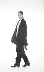Load image into Gallery viewer, Left side full body view of a woman wearing the mxmatthildur beth cardigan. This cardigan has long sleeves and a draped open front. The cardigan is black with ivory stitching.
