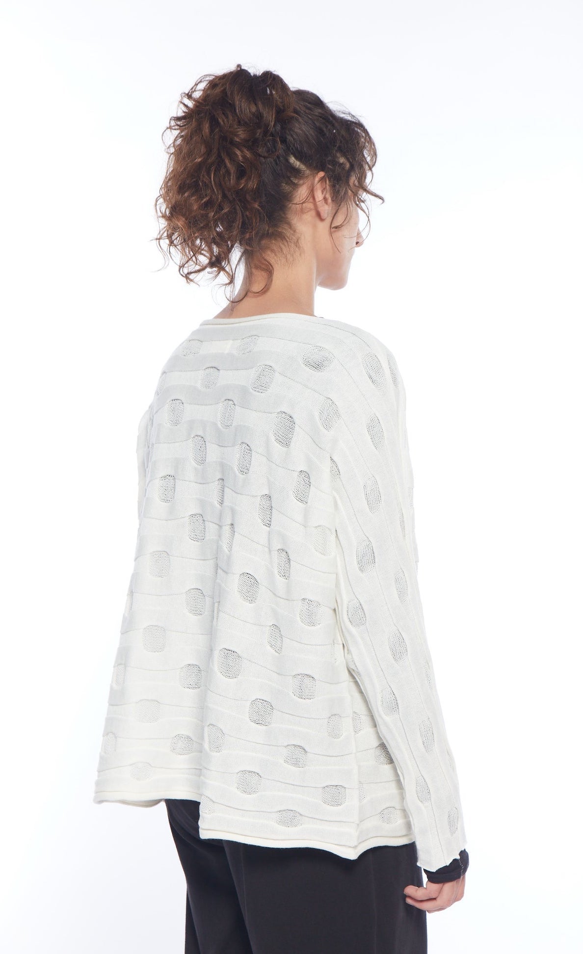 Back top half view of a woman wearing the mxmatthildur bubble sweater. This sweater features a bubble/jacquard textured fabric print, long sleeves, a boxy shape, and a boat neck.