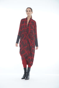 Front full body view of a woman wearing the mxmatthildur carly dress. This long sleeve dress has a red and black plaid print. It is also knotted in the front and gathers in the middle.