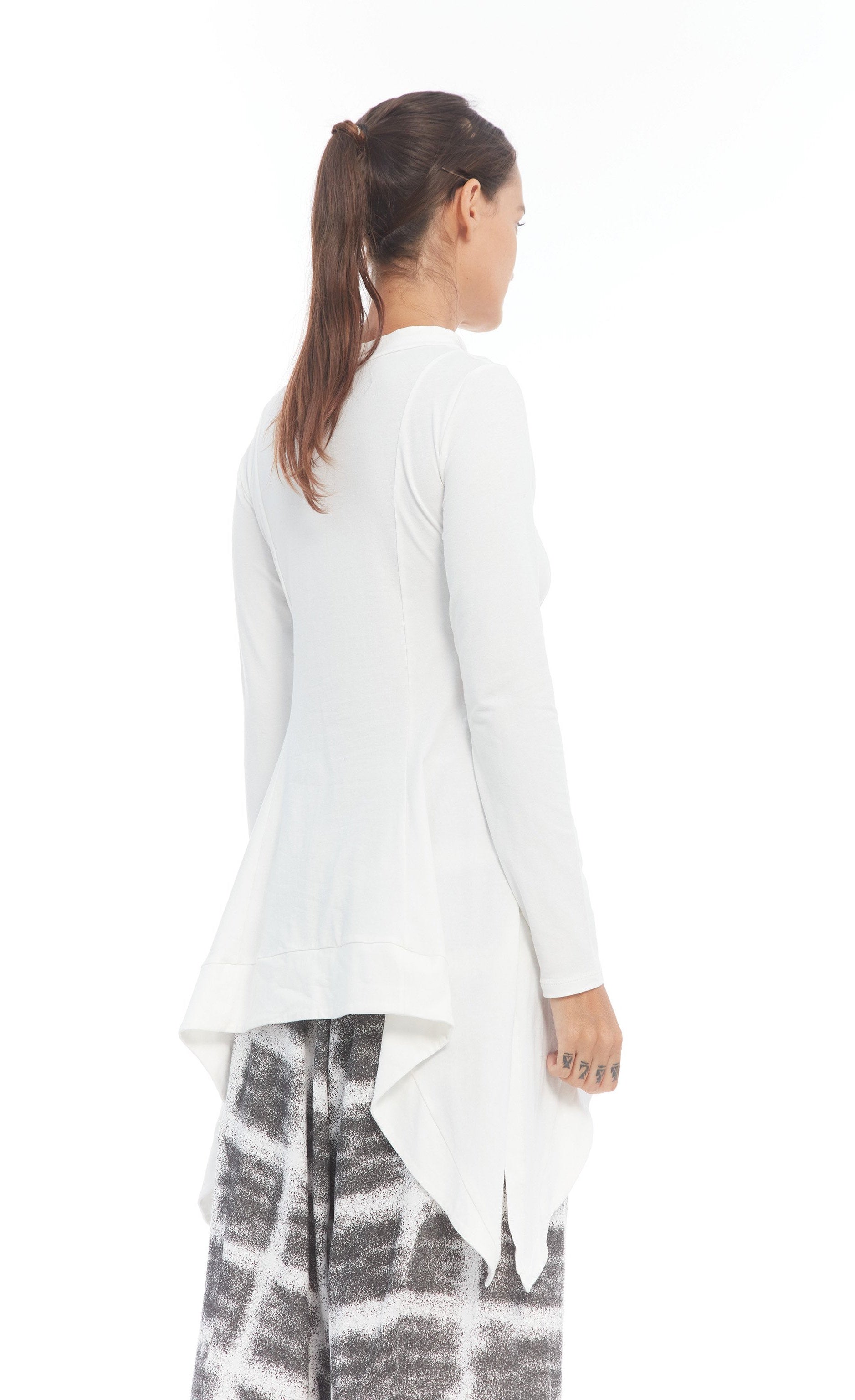 Back right side top half view of a woman wearing the mxmatthidlur lana top in white. This top has long sleeves, longer sides, and a high boat neck.