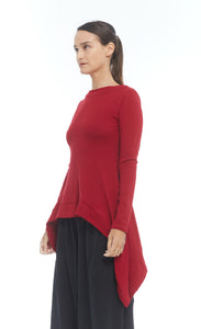 Front left side top half view of a woman wearing the mxmatthidlur lana top in red. This top has long sleeves, longer sides, and a high boat neck.