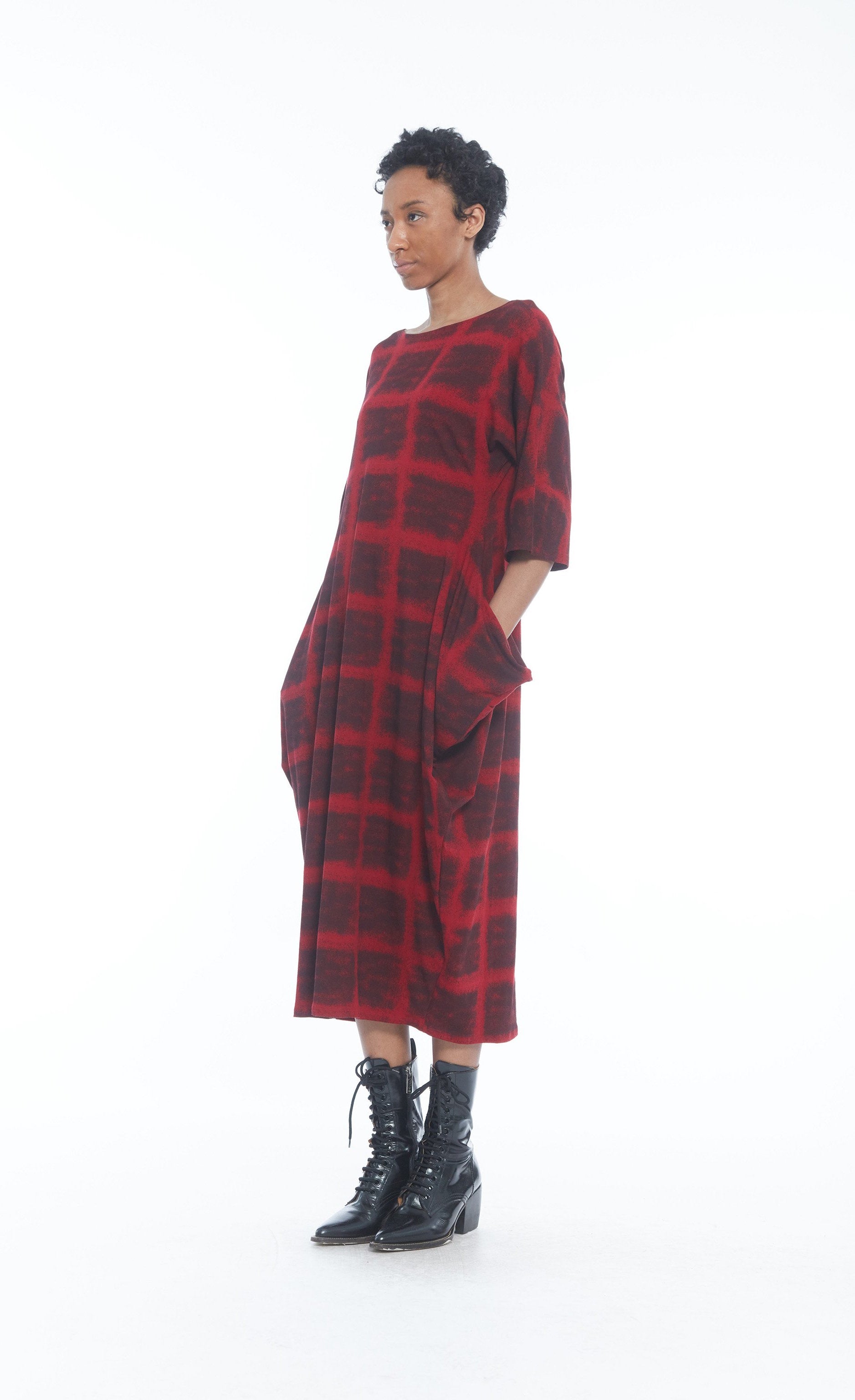 Front full body view of a woman wearing the mxmatthildur mavis dress in a red and black plaid print. This dress has 3/4 length sleeves, large pockets, and sits below the knees.