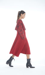 Load image into Gallery viewer, Front right side full body view of a woman wearing the mxmatthildur vonji sweater. This sweater is red and black plaid patchwork. The sweater has long sleeves and is being worn as a cropped topper with a red dress.
