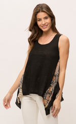 Load image into Gallery viewer, Front top half view of a woman wearing the Mystree Sleeveless Ruffle Hem Top. This tank top has a solid black front with mixed floral print running slightly slanted and vertically down the sides. The bottom of the top is shorter in the front and longer on the sides.
