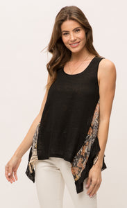 Front top half view of a woman wearing the Mystree Sleeveless Ruffle Hem Top. This tank top has a solid black front with mixed floral print running slightly slanted and vertically down the sides. The bottom of the top is shorter in the front and longer on the sides.