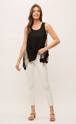 Load image into Gallery viewer, Front full body view of a woman wearing white pants and the Mystree Sleeveless Ruffle Hem Top. This tank top has a solid black front with mixed floral print running slightly slanted and vertically down the sides. The bottom of the top is shorter in the front and longer on the sides.
