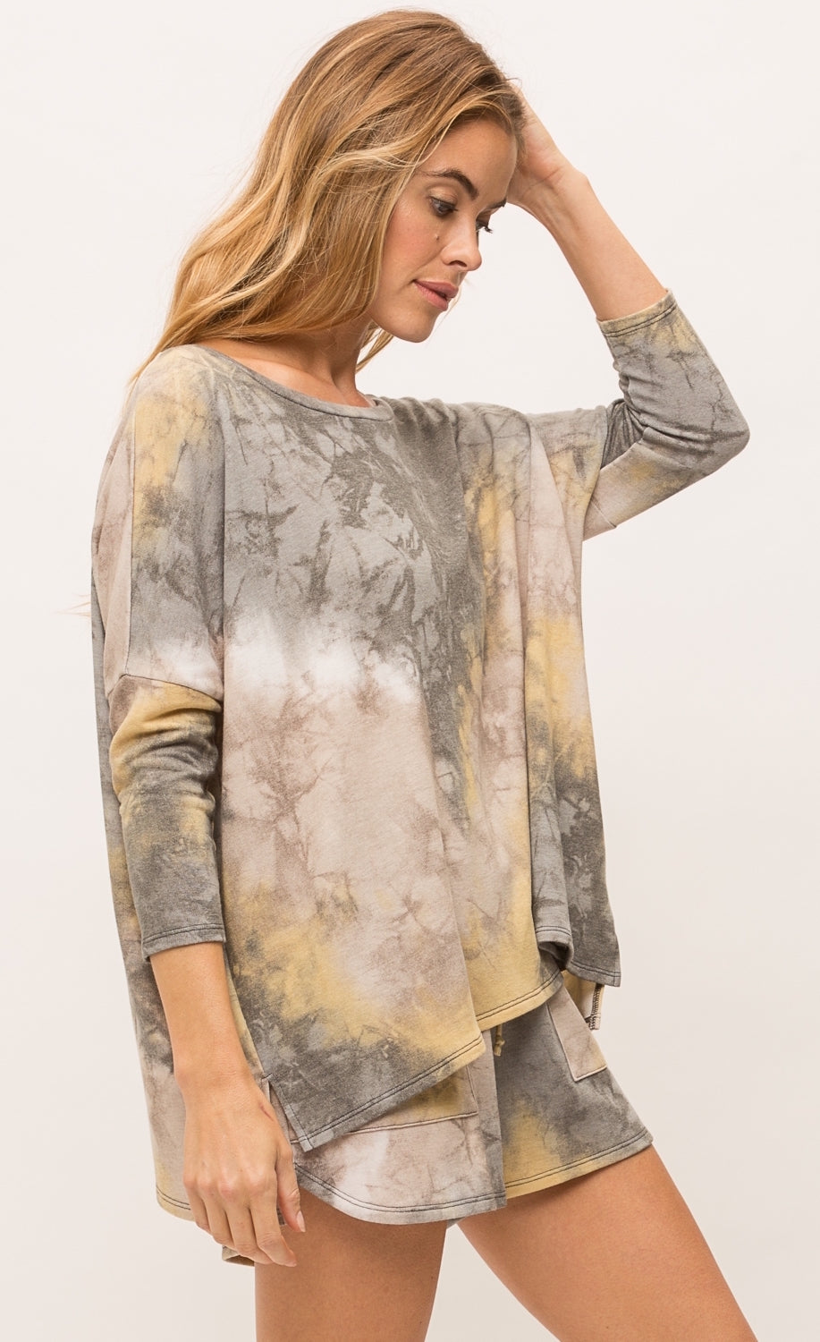 Right side top half view of a woman wearing the mystree bluestone tie dye top. This top is a grey and yellow tie top with long sleeves and a boxy fit.