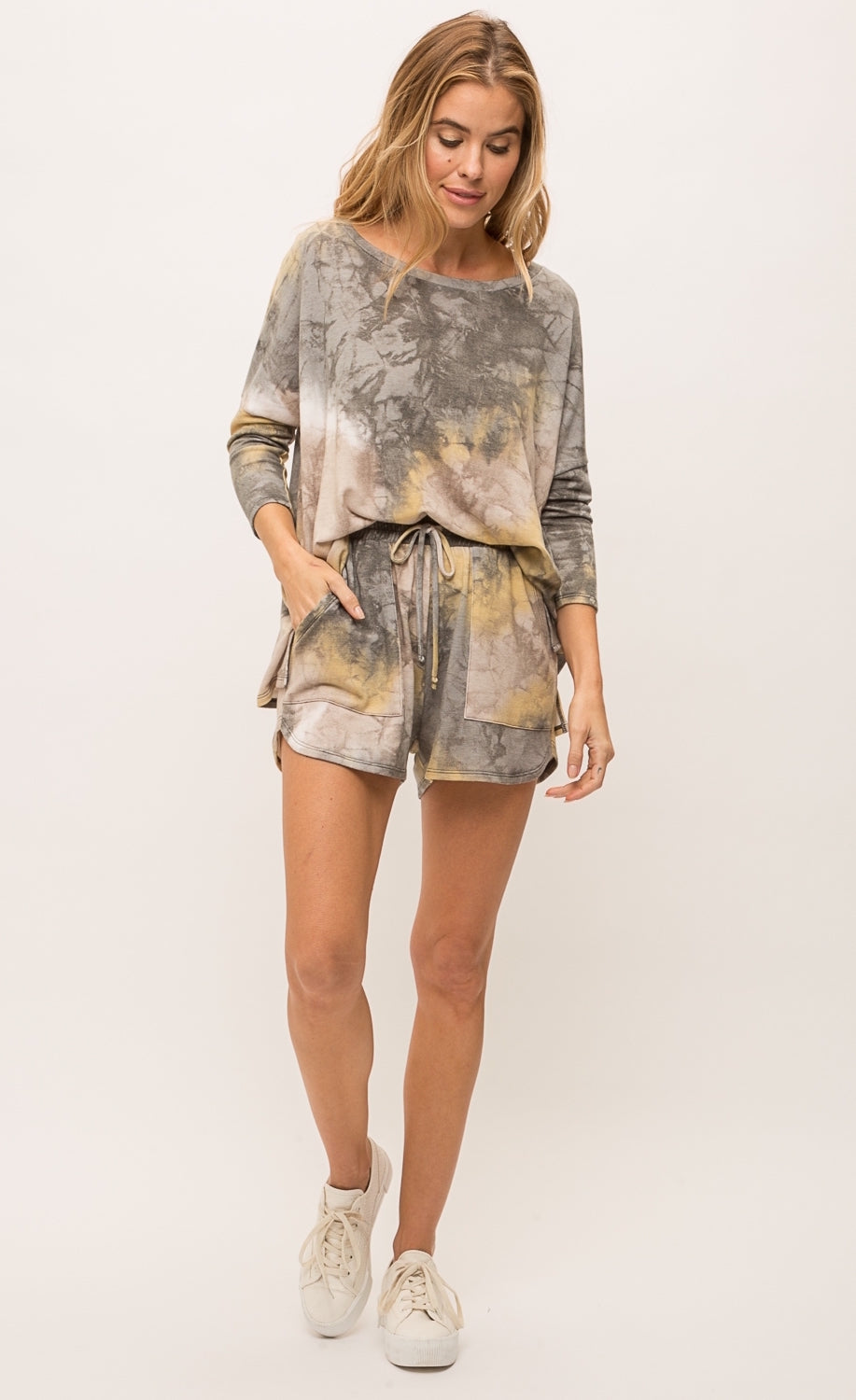 Front full body view of a woman wearing the mystree bluestone tie dye top. This top is a grey and yellow tie top with long sleeves and a boxy fit.