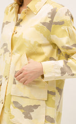 Load image into Gallery viewer, Close up front view of a woman with her thumb in the pocket of the Mystree Camo Jacket she is wearing. This jacket is different shades of yellow camo with some brown mixed in. The close up focuses on the jacket cuff and large, front left-sided pocket.
