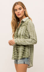 Load image into Gallery viewer, Left sided, top half view of a woman wearing the Mystree Flowy Tie Dye Shirt. The shirt is olive green tie dyed with a hidden button up front, two breast pockets and long sleeves.

