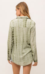Load image into Gallery viewer, Back top half view of a woman jean shorts and the Mystree Flowy Tie Dye Shirt. The shirt is olive green tie dyed with a rounded hem and long sleeves.
