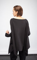 Load image into Gallery viewer, Back top half view of a woman wearing the ny77 design circle top. This top is black and flowy with fitted long sleeves. The back is solid black with a pointed hem.
