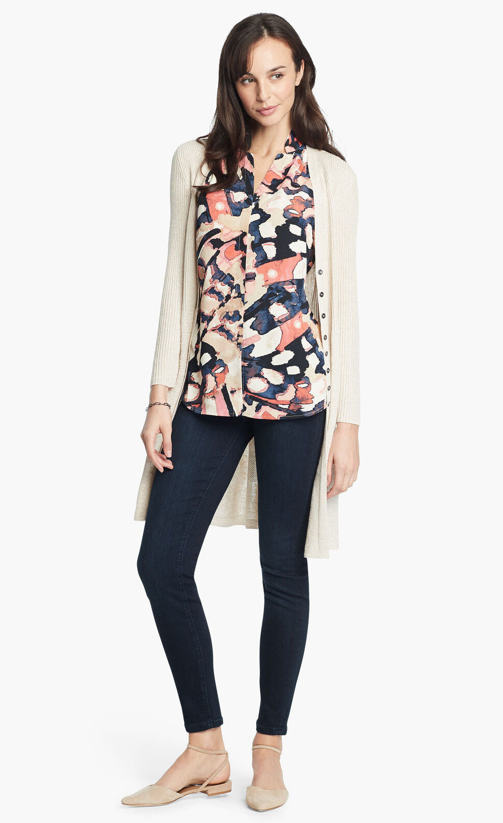 Front, full body view of a woman wearing the nic+zoe all aflutter tank under a long beige cardigan with skinny denim pants. The sleeveless tank features an abstract indigo and mixed pink print and a v-neck.