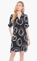 Load image into Gallery viewer, Front full body view of a woman wearing the nic+zoe billow dress. This dress is black with white swirl print all over it. The dress has a 3/4 button up front, elbow length sleeves, and front pockets.
