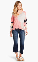 Load image into Gallery viewer, Front full body view of a model wearing the nic+zoe citrus splash sweater. This sweater is mainly pink with abstract colors of grey, blue, and creme all over it. This sweater has long drop shoulder sleeves.
