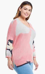 Load image into Gallery viewer, Right-sided front top half view of a model wearing the nic+zoe citrus splash sweater in a plus size. This sweater is mainly pink with abstract colors of grey, blue, and creme all over it. This sweater has long drop shoulder sleeves.
