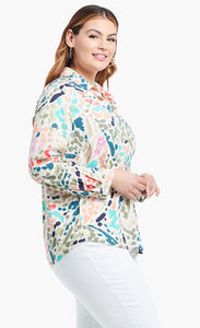 Right side, top half view of a woman wearing the nic+zoe color splash shirt. This shirt has a button up front, shirt collar, and long sleeves pushed up. It is multicolored with blue, pink, green, and salmon dots and strokes.