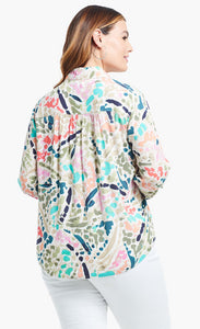Back top half view of a woman wearing the nic+zoe color splash shirt. This shirt has a soft pleated back and long sleeves. It is multicolored with blue, pink, green, and salmon dots and strokes.
