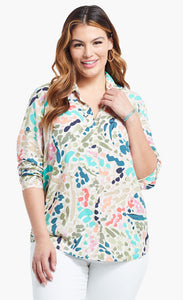 Front top half view of a woman wearing the nic+zoe color splash shirt. This shirt has a button up front, shirt collar, and long sleeves pushed up. It is multicolored with blue, pink, green, and salmon dots and strokes.