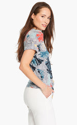 Load image into Gallery viewer, Right side top half view of a woman wearing white pants and the nic+zoe fan dot tie top. This top has a tie front, a v-neck, short sleeves, and a white background with navy dots and fanned navy, red, and nude flowers all over it.
