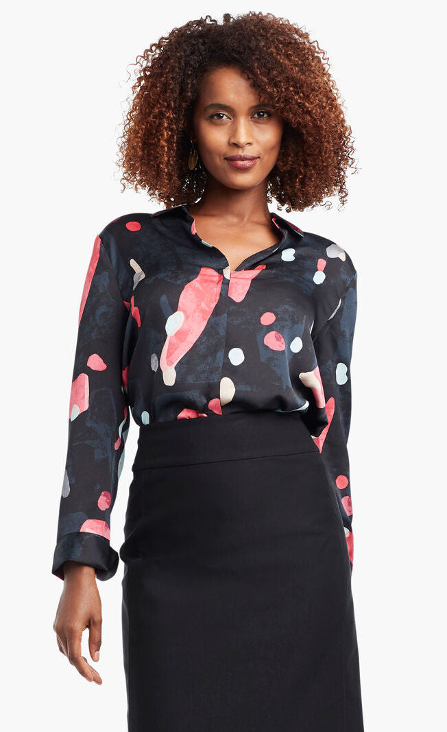 Front view of a woman wearing a black, blue & pink abstract printed kaleidoscope blouse from Nic + Zoe tucked in to a high-waisted skirt