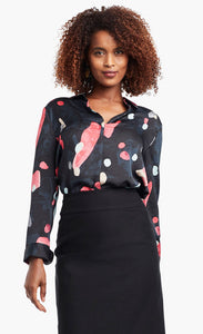 Front view of a woman wearing a black, blue & pink abstract printed kaleidoscope blouse from Nic + Zoe tucked in to a high-waisted skirt