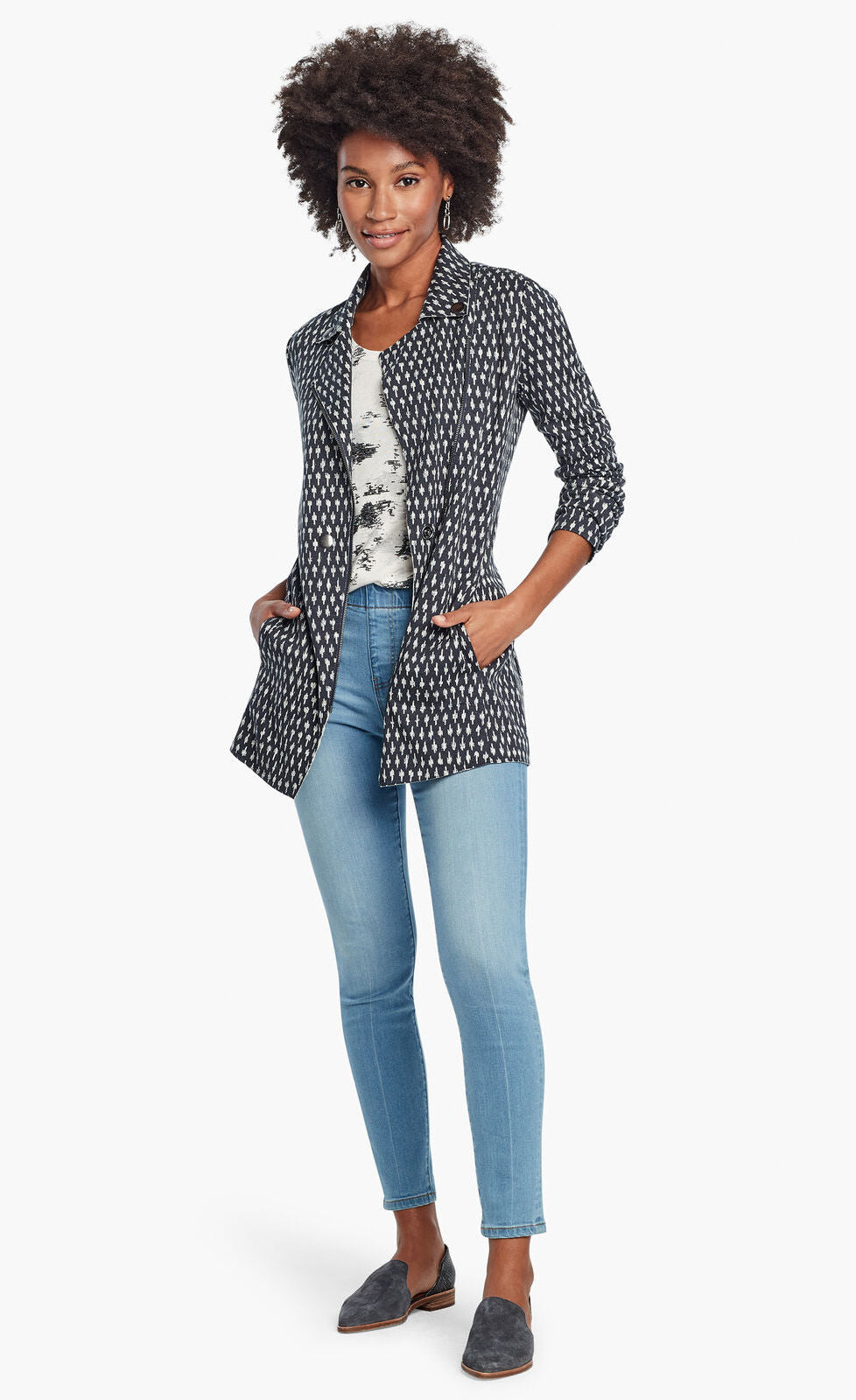 Front, full body view of a woman wearing the Nic + Zoe Ponte Ikat Jacket over a white printed top and with fitted jeans. The jacket is indigo with a white speck print all over it. It has a flat, notched lapel, and a front, off-center zipper.