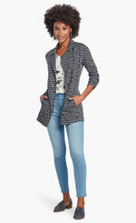 Load image into Gallery viewer, Front, full body view of a woman wearing the Nic + Zoe Ponte Ikat Jacket over a white printed top and with fitted jeans. The jacket is indigo with a white speck print all over it. It has a flat, notched lapel, and a front, off-center zipper.
