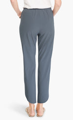 Load image into Gallery viewer, back bottom half view of a woman wearing the Shirt Tail Tech Stretch Pant in slate grey. This pant has a straight leg, a cropped length, and an asymmetrical hem.
