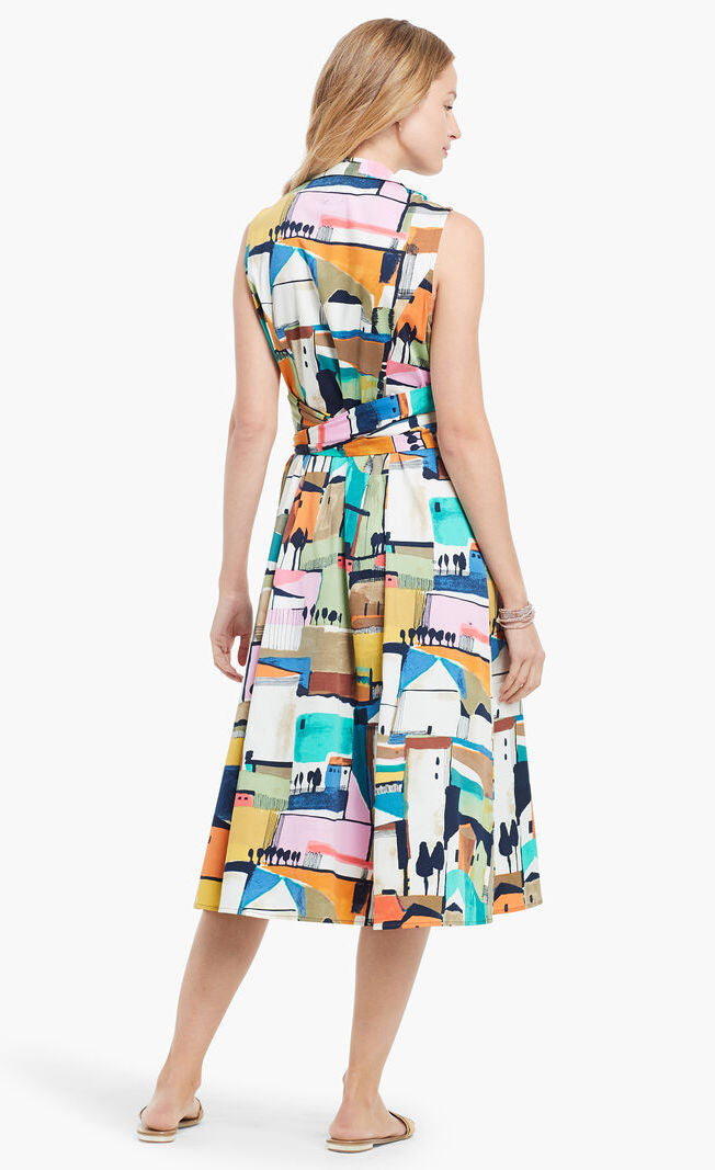 Back full body view of a woman wearing the nic + zoe street seen shirt dress. This dress has a colorful print of buildings. The back has a belted waist and the hem sits below the knees.