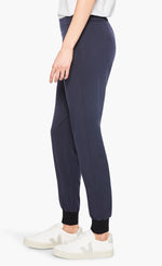 Load image into Gallery viewer, left side bottom half view of a woman wearing the nic and zoe stretch tencel jogger. These joggers are dark indigo with a tapered fit and side pockets.
