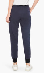 Load image into Gallery viewer, Back bottom half view of a woman wearing the nic and zoe stretch tencel jogger. These joggers are dark indigo with a tapered fit and side pockets.
