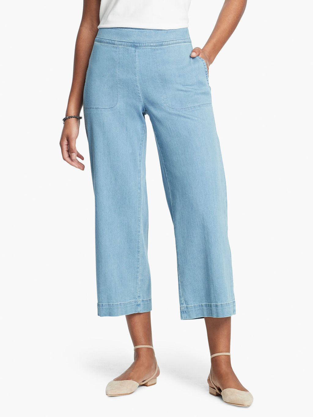 Front, bottom half view of a woman wearing a white top and the Nic + Zoe Summer day denim pant. These light wash jeans are wide legged and cropped with side pockets.