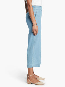 Side, bottom half view of a woman wearing a white top and the Nic + Zoe Summer day denim pant. These light wash jeans are wide legged and cropped with side pockets.