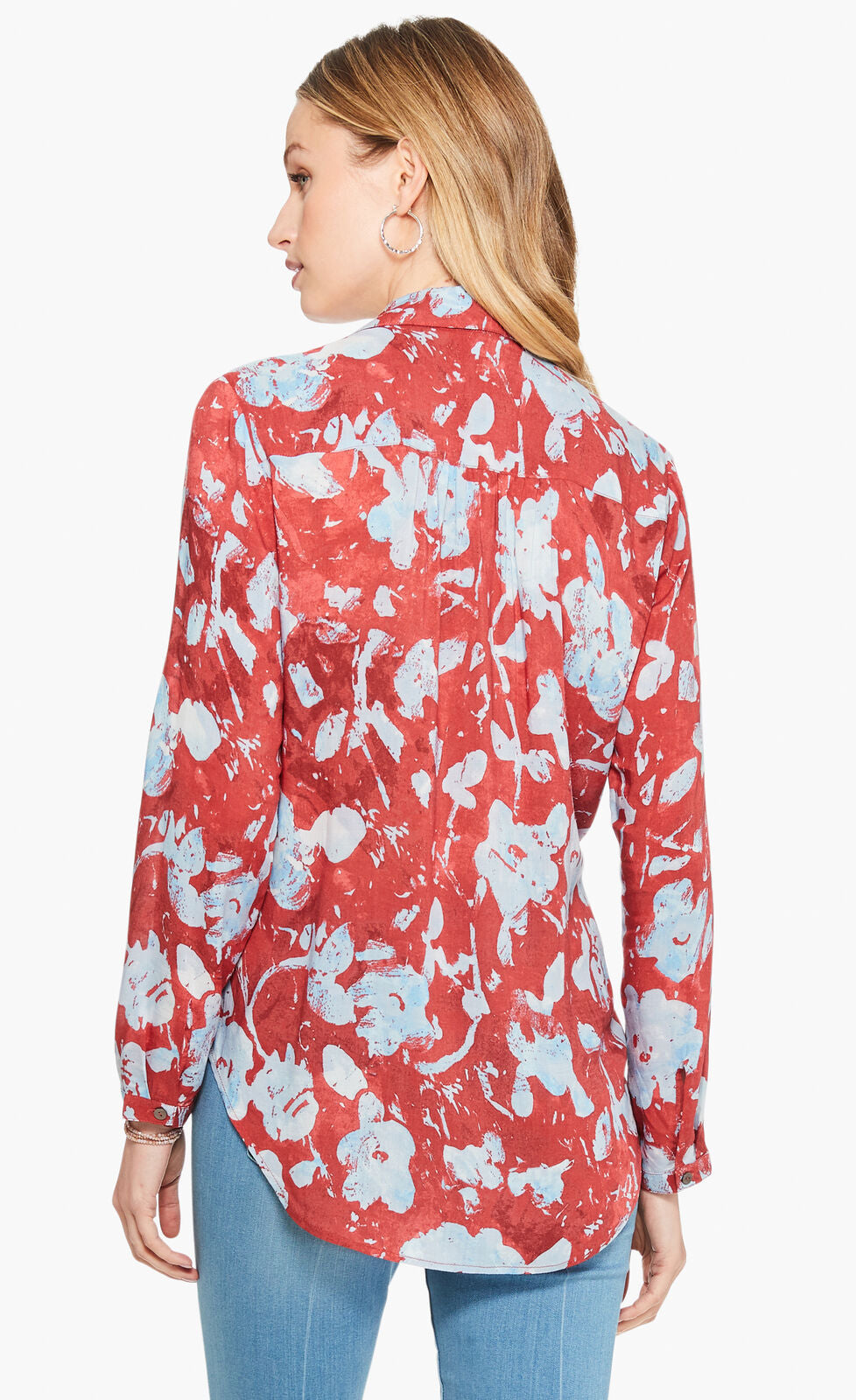 Back top half view of a woman wearing the terracotta blooms shirt from nic and zoe. This shirt has a relaxed fit with long sleeves. The shirt is red with a light blue floral print.