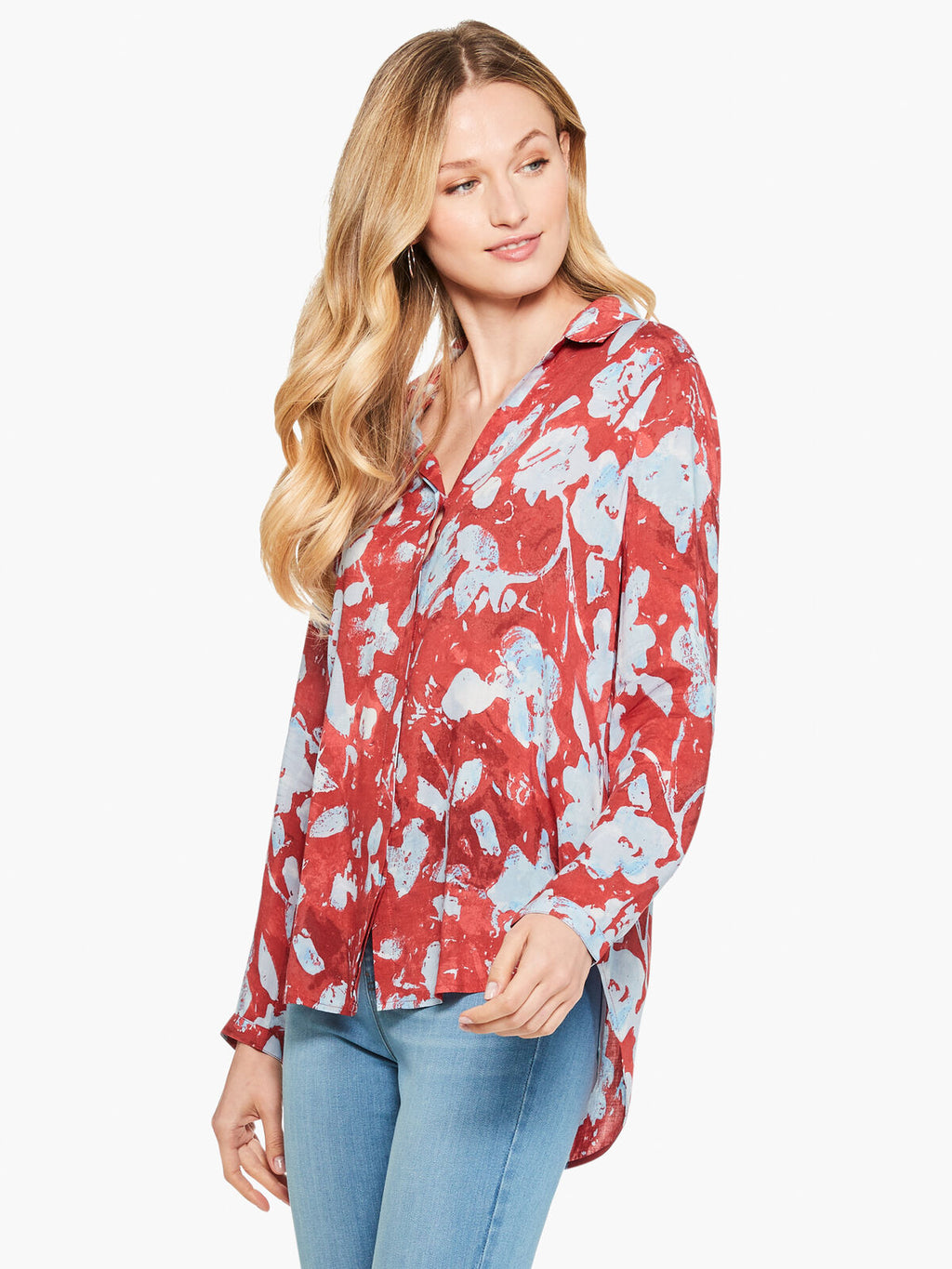 Front top half view of a woman wearing the terracotta blooms shirt from nic and zoe. This shirt has a relaxed fit with long sleeves and a button down front. The shirt is red with a light blue floral print.