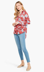 Load image into Gallery viewer, Front full body view of a woman wearing the terracotta blooms shirt from nic and zoe. This shirt has a relaxed fit with long sleeves and a button down front. The shirt is red with a light blue floral print.
