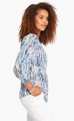 Load image into Gallery viewer, Right side top half view of a woman wearing the nic+zoe toucan shirt. This top features a blue watercolor brush stroke print, a button down front, and 3/4 length sleeves.
