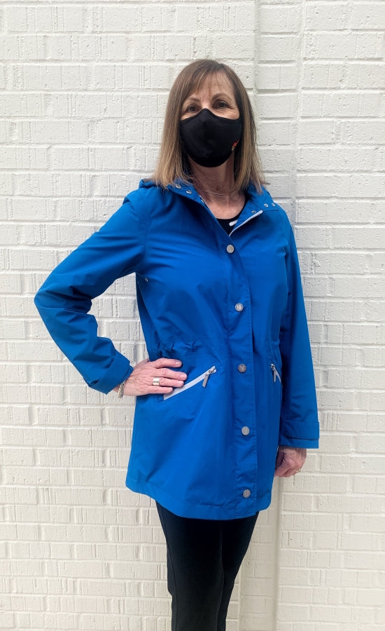 Front top half view of a woman wearing the nikki jones royal blue magic print rain jacket. This jacket has a zipper and button up front, front diagonal zipped pockets, and cuffed sleeves.