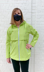 Load image into Gallery viewer, Front top half view of woman wearing the nikki jones magic print lime rain jacket. This jacket has a zipper front with two front zipper pockets, front venting over the chest and an adjustable hood and hem.
