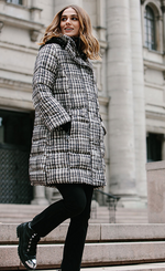 Load image into Gallery viewer, Right side action shot of a model walking around town wearing black pants and the nikki jones plaid jeannie coat. This coat is white with black and beige/grey plaid print.
