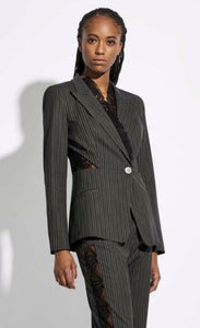 Front top half view of a woman wearing the Oblique Creations Striped Jacket. This jacket is black with white stripes. It has a single front button, long sleeves, and detailed see through mesh on the sides of the waist and as trim added to the lapels.