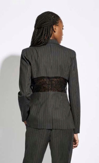 Back top half view of a woman wearing the Oblique Creations Striped Jacket. This jacket is black with white stripes. It has long sleeves and detailed see through mesh running across the back of the waist.