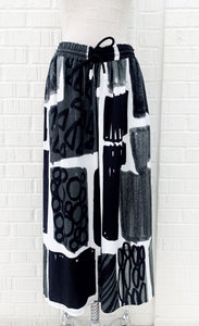 Front view of the crea concept black and white print pant. This pant has an abstract print on it, a wide leg, and an elastic waistband with a drawstring.