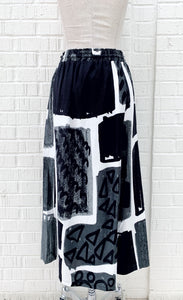 Back view of the crea concept black and white print pant. This pant has an abstract print on it, a wide leg, and an off-center back that makes it appear as a skirt.