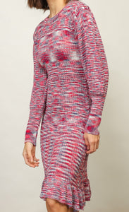 Left sided front full body view of a woman wwearing the Line + Dot Noa Sweater Dress. This dress has a mixed pink and blue knit fabric, a fitted silhouette with a ruffled hem that sits at the knees and large sleeves with fitted cuffs.